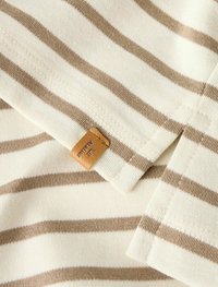 Baumwollstoff mit horizontalen cremen und hellbraunen Streifen. Enthält ein hellbraunes Etikett mit dem Text "LIT", das Nähdetails und Textur zeigt.