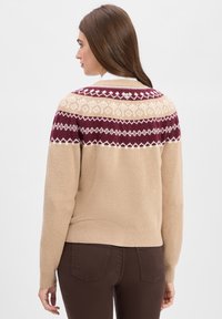 Strickpullover in Beige mit einem gemusterten, burgunderfarbenen und cremefarbenen Passe. Verfügt über lange Ärmel und einen gerippten Saum. Weicher Textur, lässige Passform.