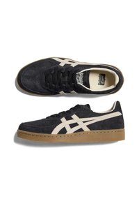 Black suede sneakers with white accents, low profile, round toe, and rubber gum sole. Features flat laces and embossed logo on the tongue.