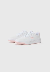 Valged tenniseskeid sujuva nahkastsuga, roosa aktsentidega kand ja tallal, ümmargune varvas ja valged paelad. Lacoste logo silmatorkavalt esindatud.