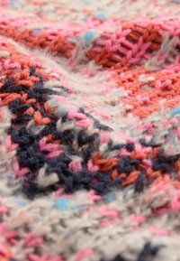 Tissu tricoté présentant un mélange de fils rose, corail, bleu et bleu marine dans un design texturé et orné avec des fibres douces et duveteuses.