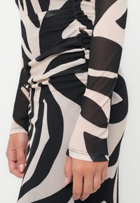 Robe à manches longues en motif abstrait noir transparent et nude avec des détails froncés sur le côté. Texture lisse, design ajusté.