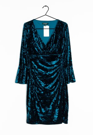 Robe bleu sarcelle en velours écrasé longueur genou avec manches longues évasées et col en V, suspendue sur un cintre noir sur fond blanc.