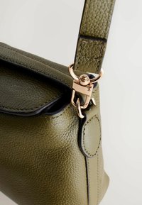 Olive rohelise nahast käekott tekstuurse viimistlusega, millel on must ääris ja kuldse tooniga metallklamber rihmal.