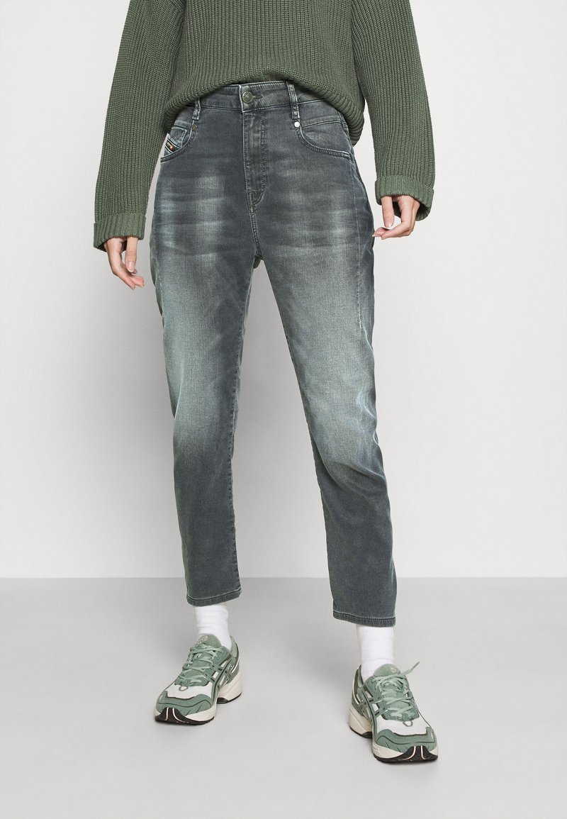 Grå denimjeans med en lätt sliten finish, rak skärning och femfickorsdesign, kombinerat med en grön tröja och sneakers.