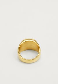 Bague dorée avec une texture lisse et polie. Présente un anneau arrondi et un design subtilement effilé sur le dessus. Aucun motif ou accent visible.