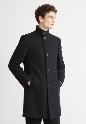 Abrigo de lana negra con cuello alto, seis botones en el frente y bolsillos laterales. Textura suave con un corte ajustado.