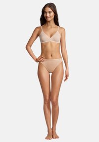 Beige Dessous-Set mit nahtlosem BH mit verstellbaren Trägern und passenden niedrighüfthaltenden Slips, gefertigt aus einem weichen, glatten Stoff.