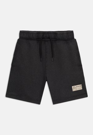 Μαύρο σορτς με ελαστική μέση και κορδόνι, πλαϊνές τσέπες και ένα μικρό μπεζ ταμπελάκι που γράφει "ΚΑΛΟΚΑΙΡΙ ΣΤΗΝ ΑΚΤΗ" στο αριστερό πόδι.