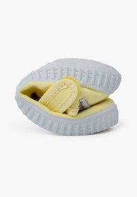 Scarpa in tessuto giallo con suola in gomma bianca, superficie testurizzata e una cinghia per una vestibilità sicura. Design compatto adatto per le calzature per bambini.
