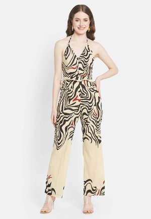 Beige jumpsuit with zebra print design in black and red, halter neckline, wide legs, and a fur belt detail. Transparent heels.