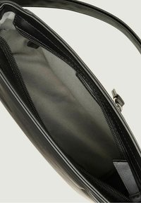 Interno di una borsa in pelle nera con una texture liscia, dotato di una tasca con zip e di un ampio scomparto principale. Design del manico resistente.