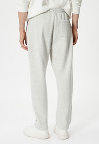 Pantalones de chándal de algodón gris con un corte relajado, que cuentan con una cintura elástica, bolsillos laterales y un bolsillo trasero. Tejido texturizado con un acabado suave.
