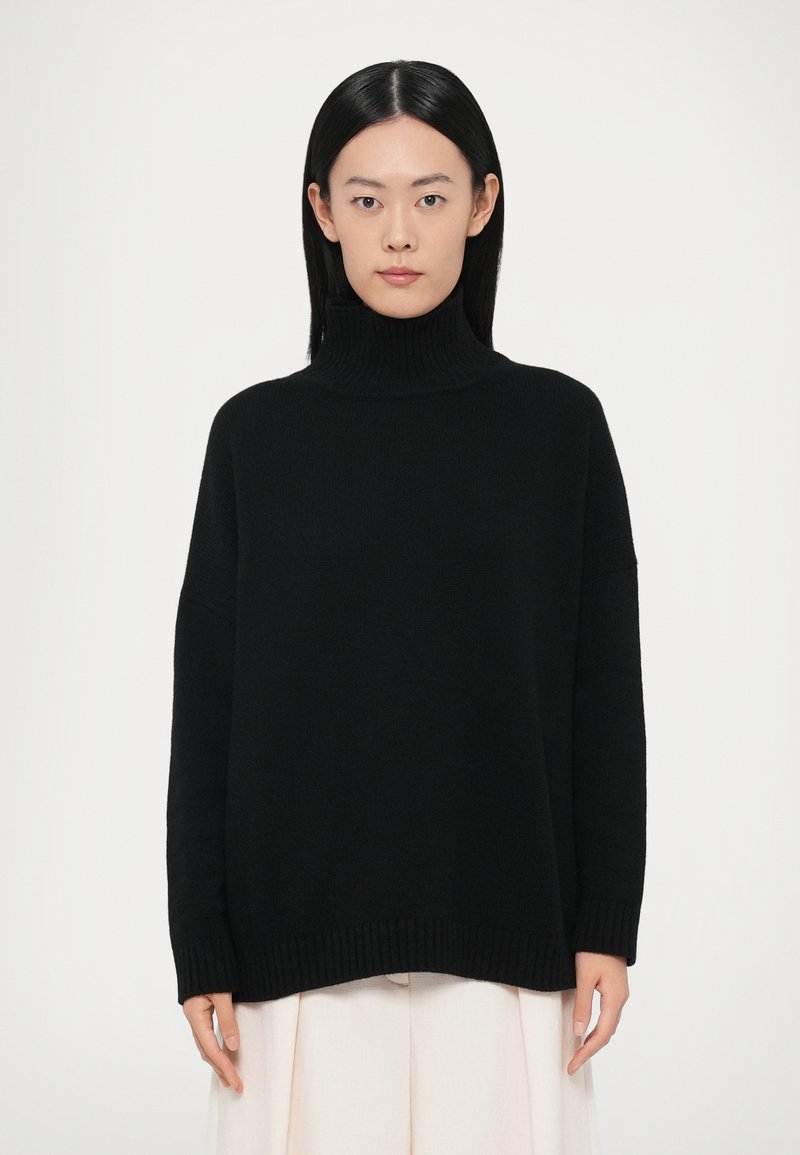 Pull noir à col montant avec une coupe ample, poignets et ourlet côtelés. Texture douce, arborant un design simple et minimaliste.