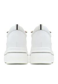 Baskets en cuir blanc avec une texture lisse, dotées d'un col rembourré, d'une bande noire contrastante sur le talon et d'une semelle épaisse texturée.
