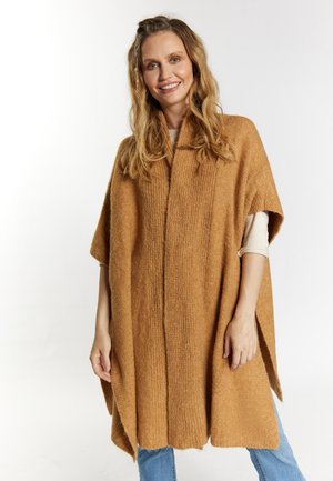 Poncho en maille marron clair avec une texture côtelée, présentant un design large et ouvert avec des manches courtes. Notable pour son tissu doux et sa coupe décontractée.