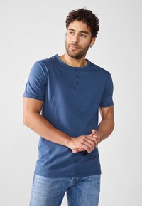 T-shirt henley a maniche corte blu in cotone, con placket a tre bottoni, scollo rotondo e texture liscia.