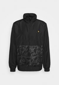 Coupe-vent noir avec un col montant, doté d'un panneau inférieur texturé avec un motif sombre, de poignets élastiques et d'un petit logo jaune sur la poitrine.