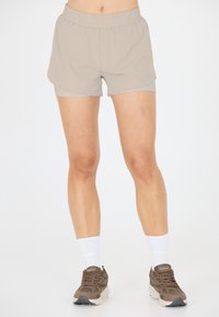 Helle beige Sportshorts mit einem elastischen Bund, die eine glatte Textur und eine lockere Passform aufweisen. Getragen mit braunen Sneakers und weißen Socken.