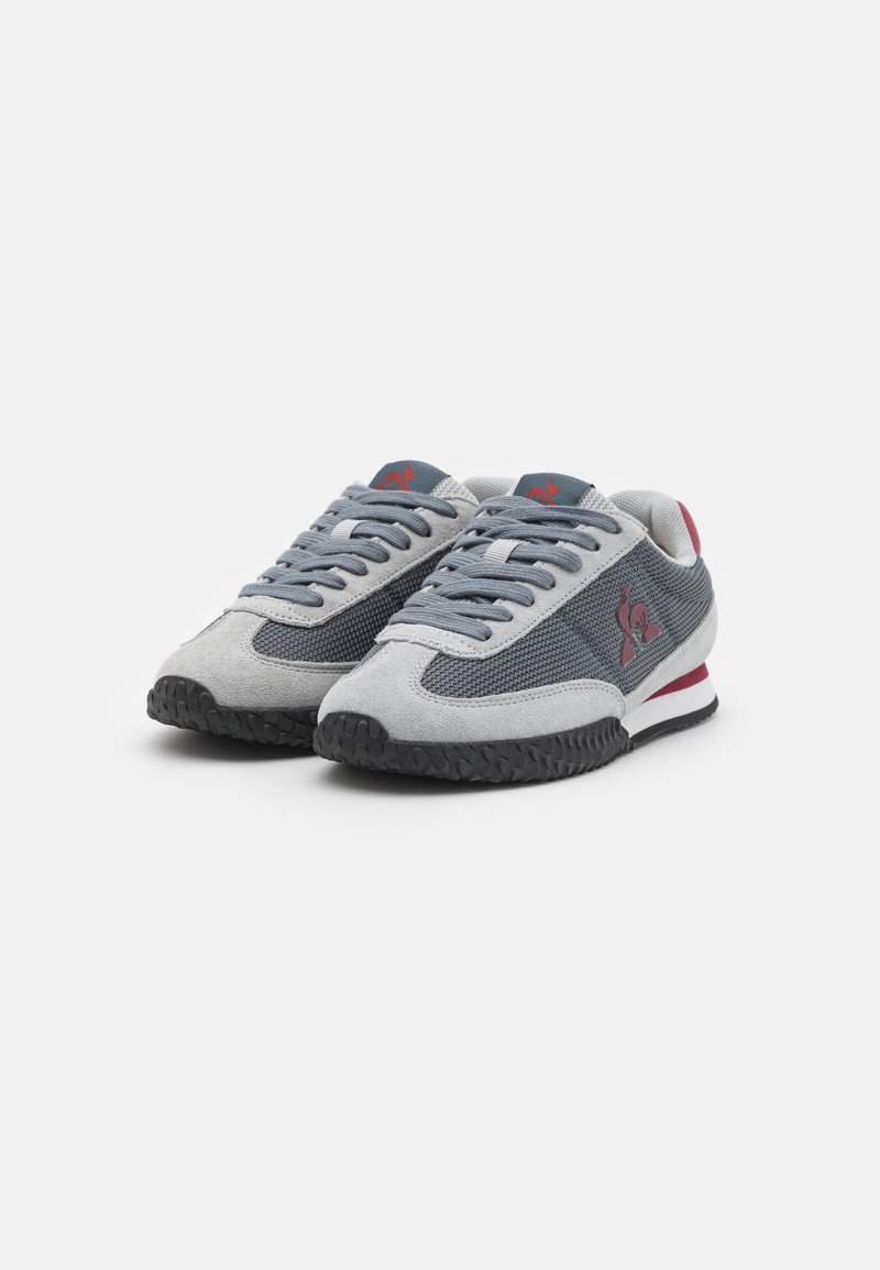 Chaussures de sport grises et noires avec un dessus en maille, des accents en daim, des lacets ronds et un logo. Dispose d'une semelle rembourrée et d'une semelle en caoutchouc.