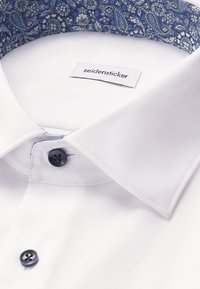 Witte dress-shirt met een gemusterde blauwe kraag. Beschikt over een subtiele textuur, knoopsluiting en een genaaid label met "seidensticker."