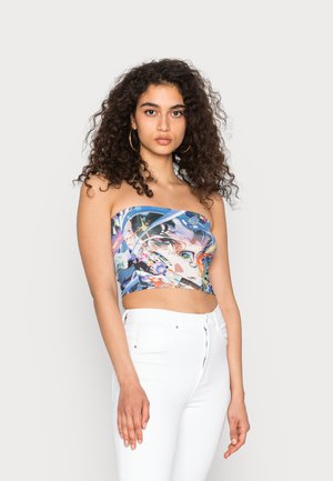 Top cropped sem alças com um padrão abstrato multicolorido em um tecido suave, combinado com calças brancas de cintura alta.