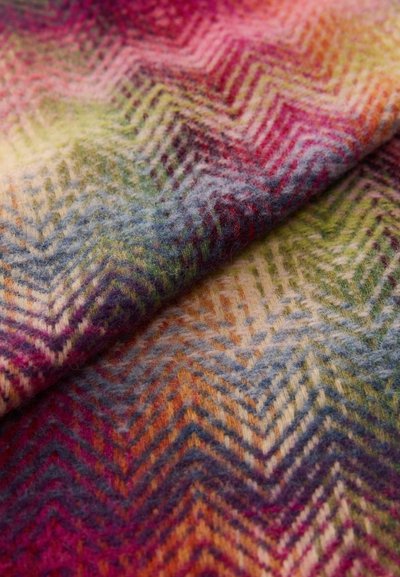 Farverigt vævet uldstof med et fiskebensmønster i nuancer af pink, lilla, grøn og creme; blød tekstur med en fuzzy overflade.