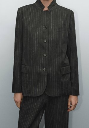 Czarna marynarka w prążki z kołnierzem mandaryńskim, wyposażona w pięć guzików, dwie kieszenie z przodu i teksturowany materiał.