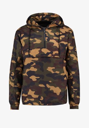 Chaqueta cortavientos de camuflaje con capucha, cierre de media cremallera en el frente, puños elásticos y una combinación de patrones en verde, marrón y beige. Material ligero.