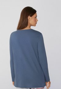 Blauwe top met lange mouwen van zacht materiaal, met een eenvoudige ronde halslijn en rechte snit, met een gladde textuur en geen zichtbare patronen.