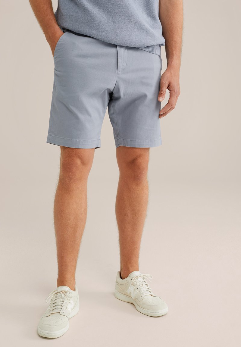 Světle modré bavlněné šortky, rovného střihu, kapsy po stranách, hladká textura, doplněné bílými teniskami.