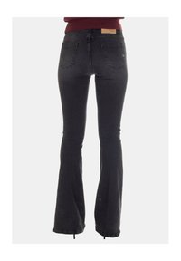 Jeans neri a zampa con vita media, dotati di due tasche posteriori e un tessuto testurizzato. La cintura mostra una toppa in pelle con il logo del marchio.