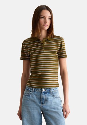Femme portant un polo à manches courtes vert olive avec des rayures horizontales blanches et marron et un jean taille haute bleu clair.