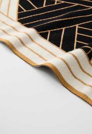 Manta tejida con un patrón geométrico en negro y crema con acentos dorados; bordes con flecos; marcada con "MISSONI."