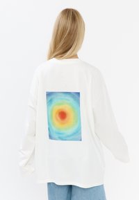Witte lange mouw t-shirt met een kleurrijk cirkelvormig aquarelontwerp op de achterkant, met een relaxte pasvorm en geribde halslijn.