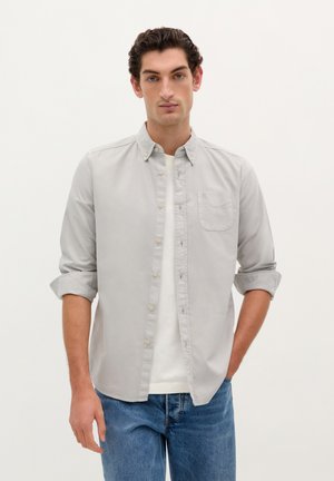 Lichtgrijs button-up overhemd van katoen, met een borstzak, opgerolde mouwen en een klassieke kraag. Gecombineerd met denim jeans.