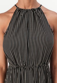 Juoda ir smėlio spalvos dryžuota halterio suknelė su suplota apykakle, skylutės detale ir guminiu liemeniu, pagaminta iš lengvos medžiagos.