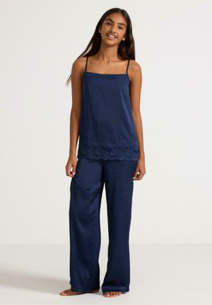 Marineblauwe zijden camisole met dunne bandjes, kantdetails aan de rand, gecombineerd met loszittende marineblauwe zijden broeken met zijzakken.