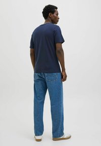 Mørkeblå bomulds-T-shirt med rund halsudskæring, korte ærmer og en afslappet pasform, parret med lyseblå lige bukser og hvide sneakers.