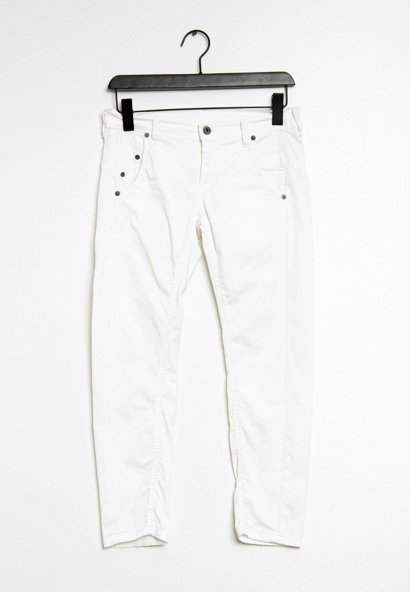 Pantalons en coton blancs sur un cintre noir. Comprend des poches avant, cinq passants de ceinture, des accents en métal pour le bouton et les rivets, et un design slim.