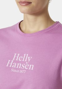 Světle růžové bavlněné tričko s kulatým výstřihem a bílým potiskem "Helly Hansen Since 1877" na přední straně. Měkká textura.