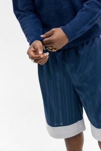 Navy blue striped shorts with a smooth texture and a contrasting gray hem. The wearer adjusts the cuff of a fuzzy navy sweater.