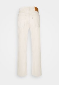 Jean en denim blanc à jambe droite, avec des poches arrière et une étiquette en cuir marron à la taille. Texture lisse, design décontracté.