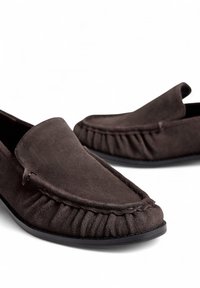 Pruuni nahast loafersid, millel on ümar nina, kokku kogutud detailid ees ja sujuv kummist tald, mis tagab parema haarde.