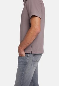 Lichtgrijze polo met korte mouwen, met een zachte textuur en zijsplitaccenten, gecombineerd met slim-fit lichtblauwe spijkerbroek.
