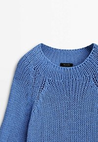 Jasnoniebieski sweter dziany z okrągłym dekoltem i ażurową strukturą. Posiada rękawy raglanowe oraz czarną metkę z nazwą marki wewnątrz kołnierza.