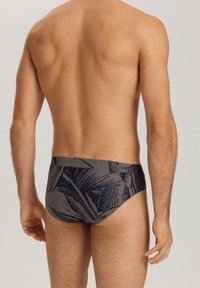 Slip da nuoto da uomo in blu navy scuro con un motivo a foglie testurizzato, caratterizzati da un design aderente e una vita elasticizzata per comfort e supporto.