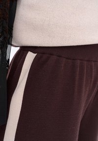 Bordeaux joggerbroeken met een zachte textuur, voorzien van een contrasterende crèmekleurige zijstreep en een comfortabele elastische tailleband.