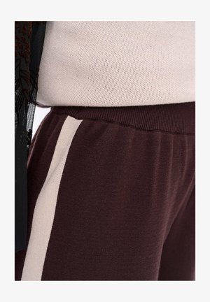 Maroon jogger pants with a soft texture, featuring a contrasting cream side stripe and a comfortable elastic waistband.