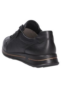 Zapato de cuero negro con puntera redondeada, detalles de costura sutiles, cierre de cremallera y una suela de goma texturizada con una franja de acento en bronce.